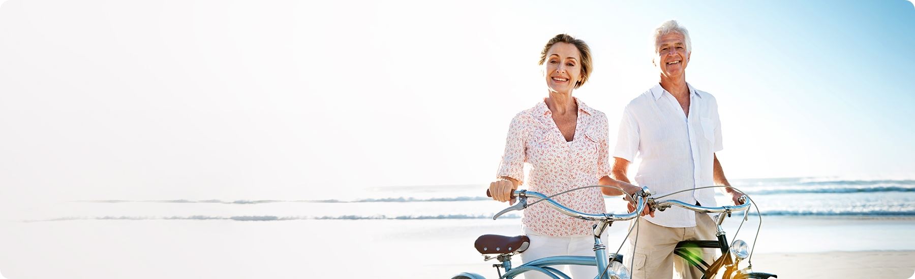 elderly people on the beach walking bikes