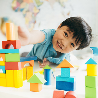 Preschool child playing on the floor with blocks.